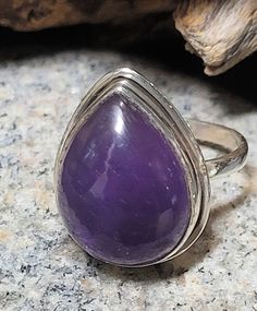 This is a sterling silver and garnet ring. The stone is 3/4 of an inch tall. Amethyst is said to act as protection and to disperse negative energy. This is a new, unworn, vintage store stock ring. It comes in a jewelry box for gifting. Silver Teardrop Rings With Spiritual Style, Silver Spiritual Teardrop Ring, Spiritual Silver Teardrop Ring, Spiritual Silver Amethyst Ring, Spiritual Teardrop Gemstone Rings, Purple Teardrop Gemstone Rings, Mystical Amethyst Ring In Sterling Silver, Mystical Sterling Silver Amethyst Ring, Spiritual Sterling Silver Gemstone Ring