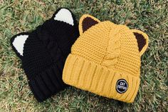 two knitted hats laying on the grass