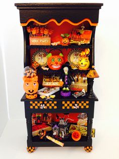 an old fashioned halloween display cabinet with decorations on the top and bottom shelves, all decorated in orange and black