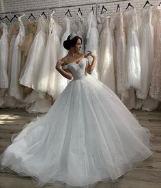 a woman in a white wedding dress standing next to dresses