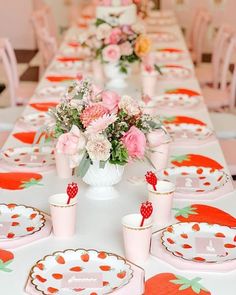 the table is set with plates, cups and vases filled with flowers on them