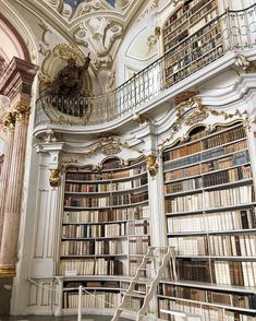 an elaborately decorated room with many bookshelves and stairs leading up to the second floor