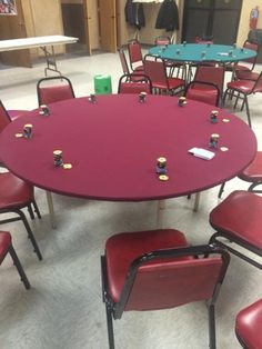 a round table with red chairs around it in a room filled with tables and chairs