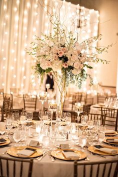 a tall vase filled with white flowers on top of a table