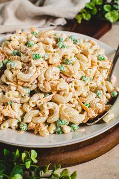 a plate full of macaroni and peas with a spoon in it on a table