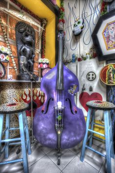 an artistic image of a purple cello in a room with stools and other items