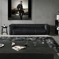 a living room filled with black furniture and a painting on the wall above it's coffee table