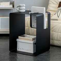 a black table with some books on it and a white couch in the back ground