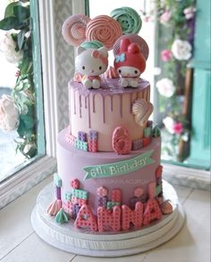 a pink cake with hello kitty decorations on top