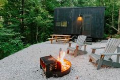 two adiron chairs sitting next to a fire pit in the middle of a forest