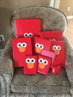 some red boxes with eyes and nose are sitting on a chair