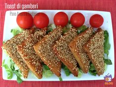 four pieces of bread with sesame seeds and cherry tomatoes on top sit on a white plate