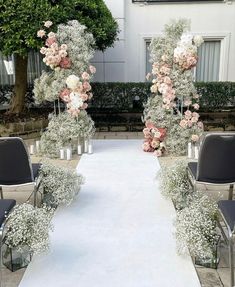 an outdoor ceremony setup with chairs and flowers on the aisle, surrounded by greenery