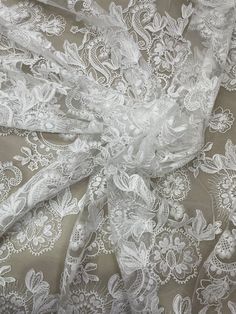 the fabric is white and has many flowers on it, as well as an intricate design