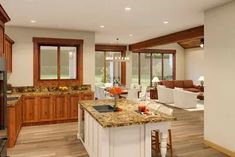 a large kitchen with an island in the middle and wood trimming on the walls