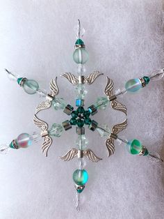 a snowflake made out of glass beads and metal wings on a white background