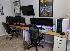 a computer desk with three monitors and a cat sitting on the floor in front of it