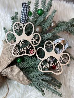 two wooden ornaments with dog's paw prints on them, hanging from a christmas tree