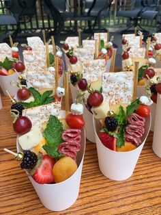 small cups filled with fruit and cheese on sticks