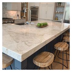 a large kitchen island with stools in front of it and an oven on the other side