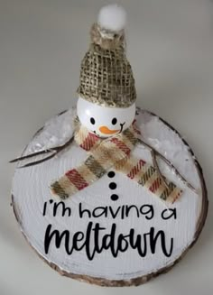 a snowman is sitting on top of a wood slice that says i'm having a meltdown