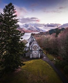 an aerial view of a church with mountains in the back ground and trees on either side