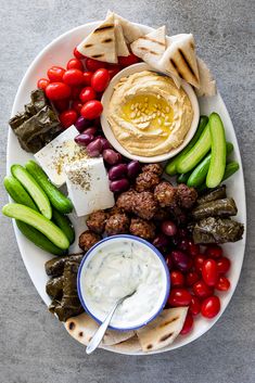 a white plate topped with meat and veggies next to pita breads