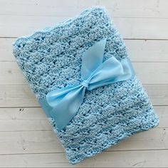 a blue crocheted blanket with a light blue bow on the front and back