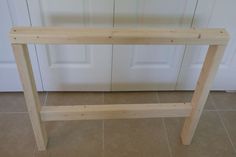 a wooden table sitting in front of a door on tile floor next to a white door