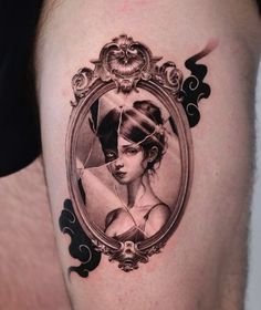 a woman's portrait in a frame tattoo on the right side of her thigh