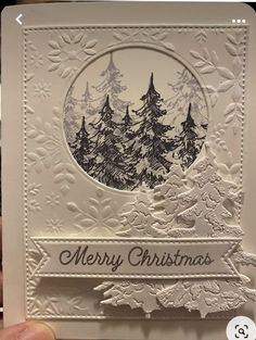 a handmade christmas card with trees and snowflakes on the front, in white paper