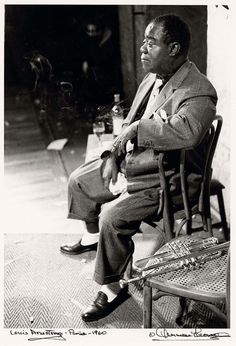 a black and white photo of a man sitting in a chair looking off into the distance