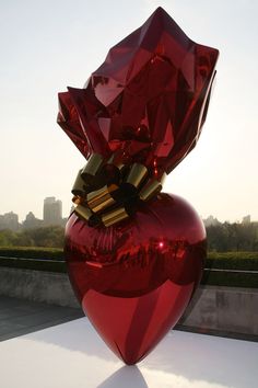 a large red vase sitting on top of a white table