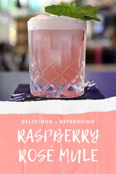 a pink drink sitting on top of a table next to a sign that says delicious and refreshing raspberry rose mule