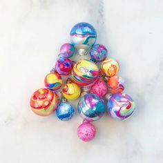 a pile of colorful marbled balls on a white counter top, with one in the middle surrounded by smaller ones