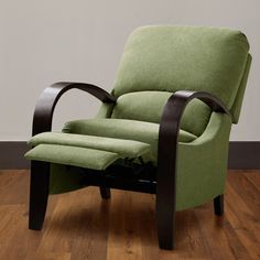 a green recliner chair sitting on top of a hard wood floor next to a white wall