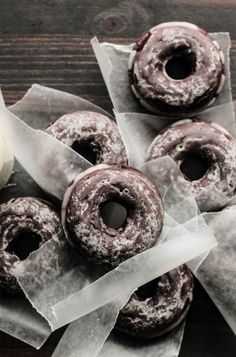 chocolate donuts with icing and sprinkles sitting on wax paper next to a white rose