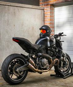 a motorcycle parked in front of a garage door with a helmet on it's head