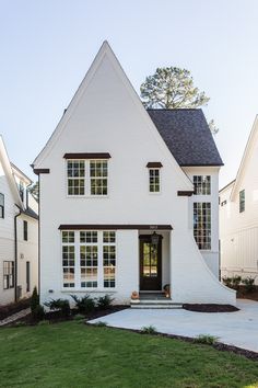 a white house with black shutters and two story windows on the front door is shown