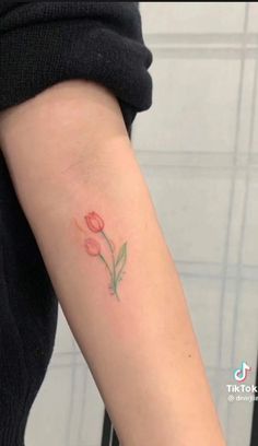 a woman's arm with a small flower tattoo on the left side of her arm