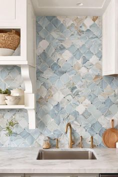 a kitchen with white cabinets and blue tile backsplash, gold faucet