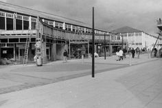 an old black and white photo of people walking in front of a building under construction