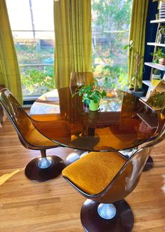 a glass dining table with chairs and a potted plant in the middle of it