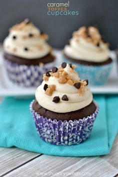 chocolate cupcakes with white frosting and sprinkles are on a blue napkin