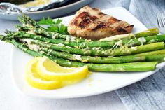 asparagus and chicken on a plate with lemon wedges