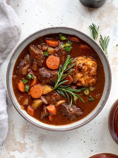 a bowl of stew with meat, carrots and gravy on the side