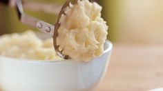 a spoon full of mashed potatoes in a white bowl