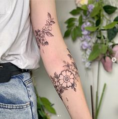 a woman's arm with flowers and leaves tattooed on the left side of her arm