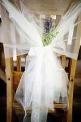 a chair with a white bow tied to it's back and some flowers on top