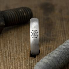 a ring sitting on top of a wooden table next to a hammer